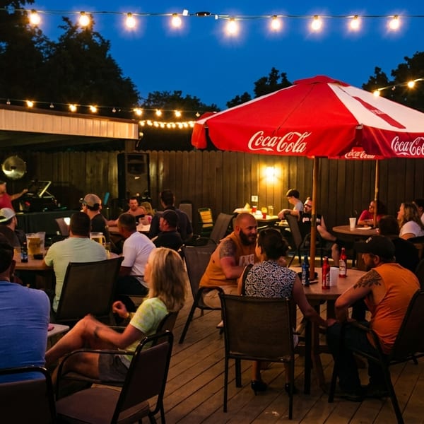 Patrons enjoying an outdoor patio at night, illuminated by string lights and a red Coca-Cola umbrella.
